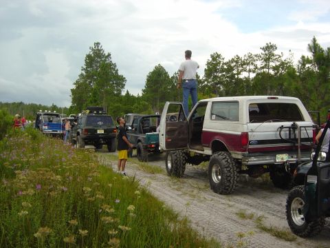 1993 Ford Bronco - Several off-road vehicles are gathered on a dirt track, with one Bronco prominently featured.