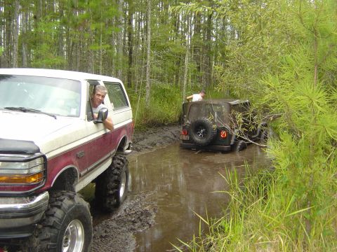 1993 Ford Bronco - Two off-road vehicles are stuck in the mud while navigating a wooded trail.