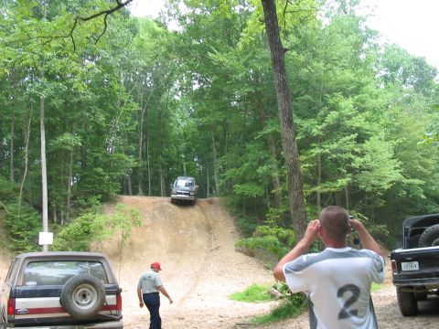 1988 Ford Bronco - A 1988 Ford Bronco navigates an off-road hill climb, with another vehicle visible in the foreground.