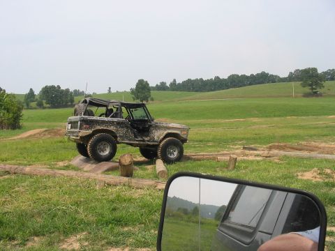 1988 Ford Bronco - This heavily modified Ford Bronco navigates an off-road course, its body covered in mud.