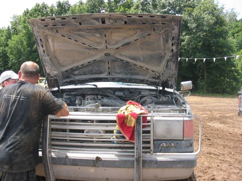 1988 Ford Bronco - Muddy 1987 Ford F-Series truck engine bay with hood open, two men inspecting the engine.