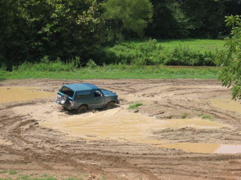 1988 Ford Bronco - This SUV is deep in the mud, with only its top and rear visible above the mire.