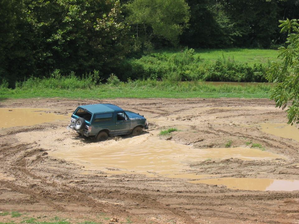 Teal SUV stuck in a mud pit, tires submerged