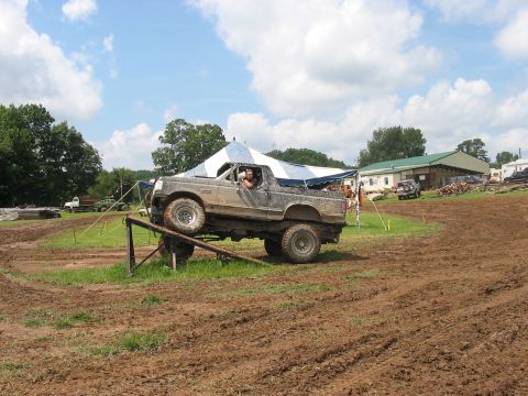 1988 Ford Bronco - A heavily modified off-road vehicle navigates an obstacle course on a sunny day.
