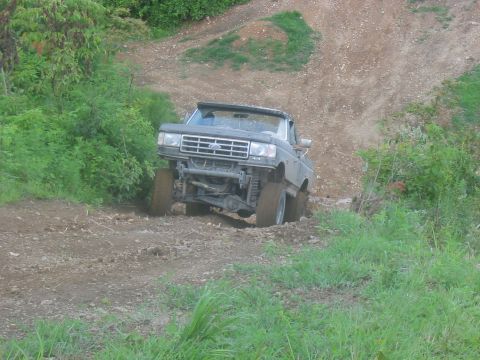 1988 Ford Bronco - This modified Ford Bronco is navigating a challenging off-road trail with steep inclines.