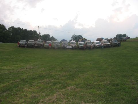 1988 Ford Bronco - A collection of 1988 Ford Broncos and similar vehicles are gathered on a grassy field under a cloudy sky.