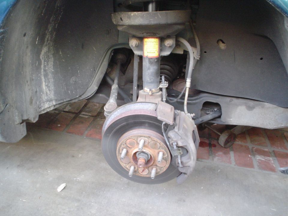 Front disc brake rotor and hub with caliper, strut visible in wheel well