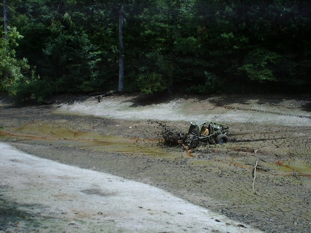 Off-road vehicle stuck in mud with trees in background