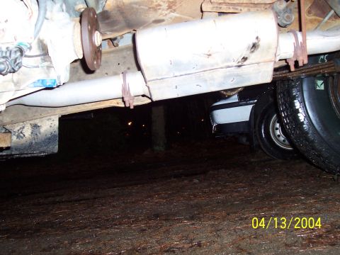 1994 Ford Bronco - The photo shows the exhaust system of a vehicle, with another car partially visible beneath it.