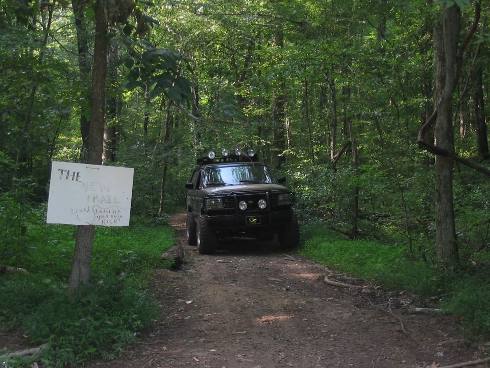 1988 Ford Bronco front view with off-road lights on a wooded trail