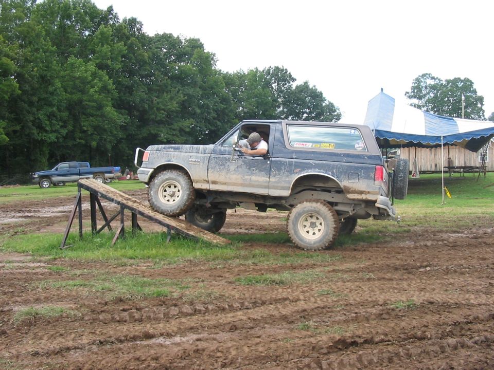 1988 Ford Bronco on a ramp with a blue pickup truck in the background