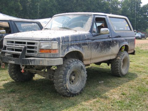 1995 Ford Bronco - This mud-covered 1995 Ford Bronco, seen from a 3/4 front angle, features off-road tires and a prominent bull bar.