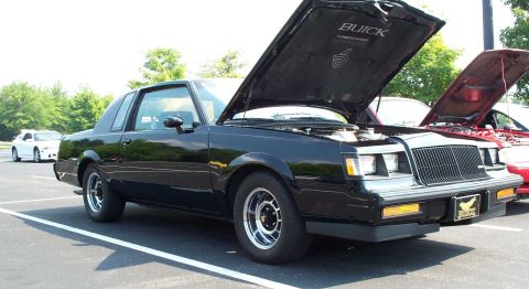 1998 Ford Crown Victoria - Black Buick Regal Grand National parked at an outdoor car meet with hood open.