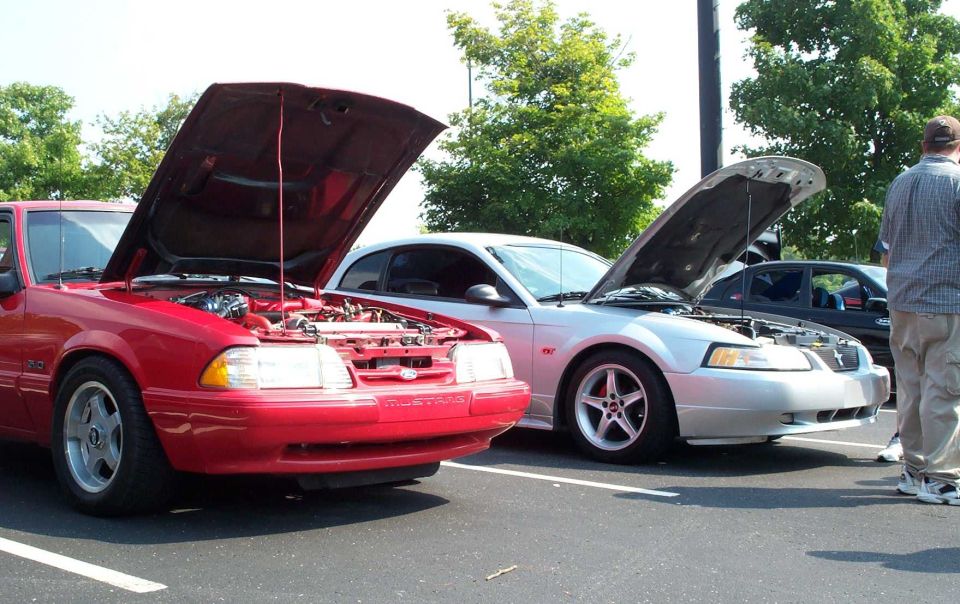 Red Fox-body and silver New Edge Mustangs with hoods open at a car show