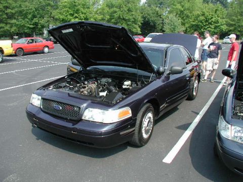 1998 Ford Crown Victoria - A dark colored 1998 Ford Crown Victoria is displayed with its hood open at an outdoor car meet.