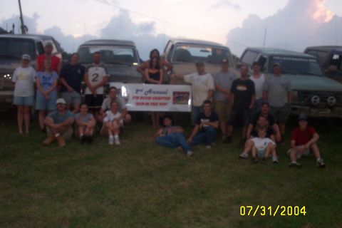 1979 Ford F-150 - A group of people gathered outdoors with several trucks in the background, posing for a photo.