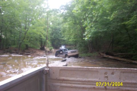 1979 Ford F-150 - Two trucks are seen driving through a muddy creek in a wooded area on July 31, 2004.