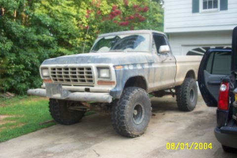 1979 Ford F-150 - This lifted 1979 Ford F-150 pickup truck is parked next to another vehicle.