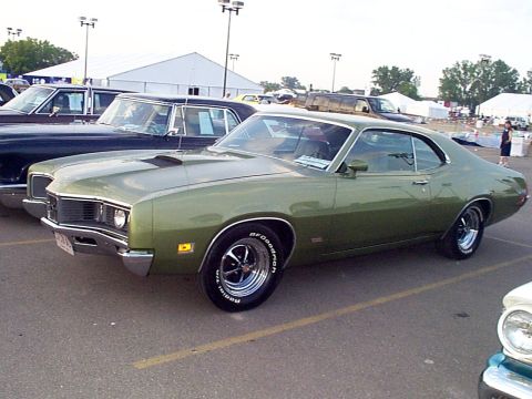 1999 Ford Taurus - This green coupe, likely from the 1970 model year, is parked alongside other vehicles.