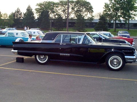 1999 Ford Taurus - A black 1960 Ford Thunderbird coupe is parked in a lot next to other vehicles.