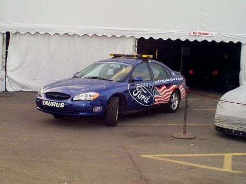 1999 Ford Taurus - A blue Ford Taurus is set up as an official pace car with patriotic decals and emergency lights.