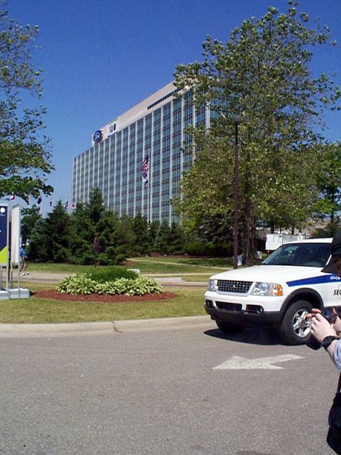 1999 Ford Taurus - A white Ford Explorer SUV, likely a 2001 model, is parked in front of a large office building.