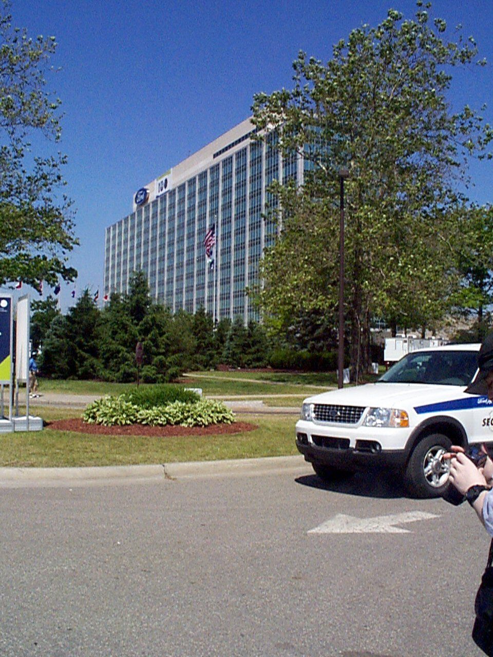 White Ford Explorer SUV with blue stripe, security markings, parked in front of a large office building