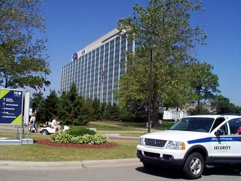 1999 Ford Taurus - A white Ford Explorer security vehicle is parked in front of a large office building, with "Ford Motor Company" and "SECURITY" visible on i…