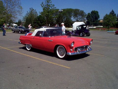 1999 Ford Taurus - A red convertible classic car is parked in a lot, with other vehicles visible in the background.