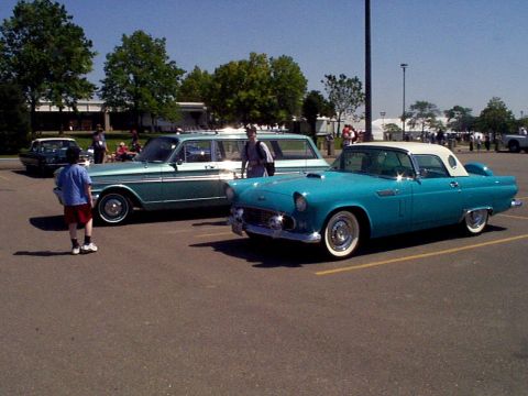 1999 Ford Taurus - A turquoise 1955 Ford Thunderbird and a teal station wagon are parked side-by-side in a lot.