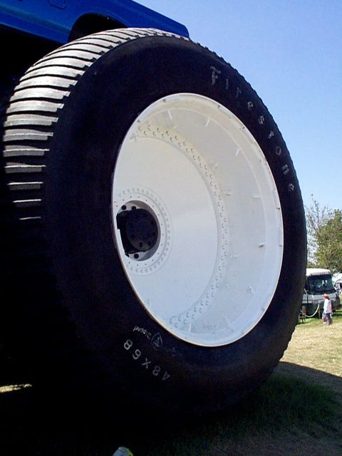 1999 Ford Taurus - This massive tire is mounted on a vehicle, with other vehicles and people visible in the background.