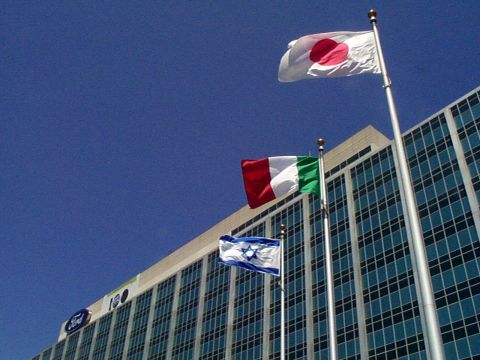 1999 Ford Taurus - A modern building with the Ford logo and '100' visible, adorned with flags from Japan, Italy, and Israel.