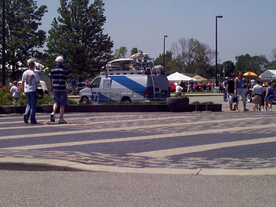 Silver and blue news van parked with equipment on its roof rack