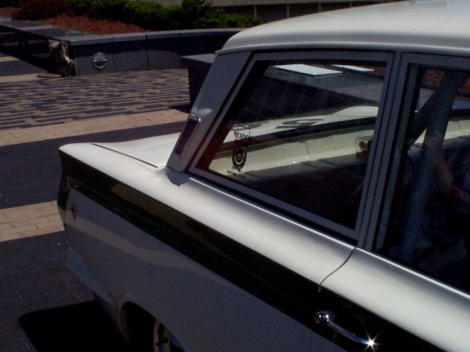 White car with black stripe, rear quarter panel visible. Supermotors.net logo at bottom right