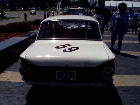 1999 Ford Taurus - A white vintage race car with a roll cage is parked outdoors, showing its rear end and license plate.