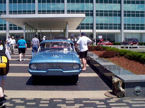 1999 Ford Taurus - A classic blue sedan is parked in front of a modern building with people walking around.