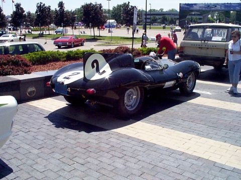 1999 Ford Taurus - A black race car with white numbers is parked on a brick surface, with other vehicles and people in the background.