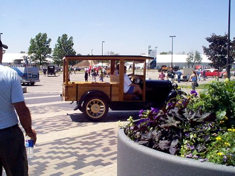 1999 Ford Taurus - A vintage wooden wagon with a driver is parked outdoors with other vehicles and people around.