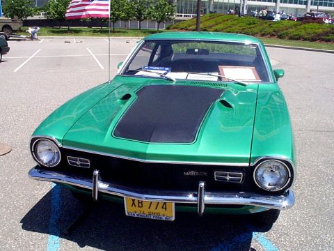 1999 Ford Taurus - A bright green 1974 Ford Maverick is parked outside on a sunny day, with an American flag flying in the background.