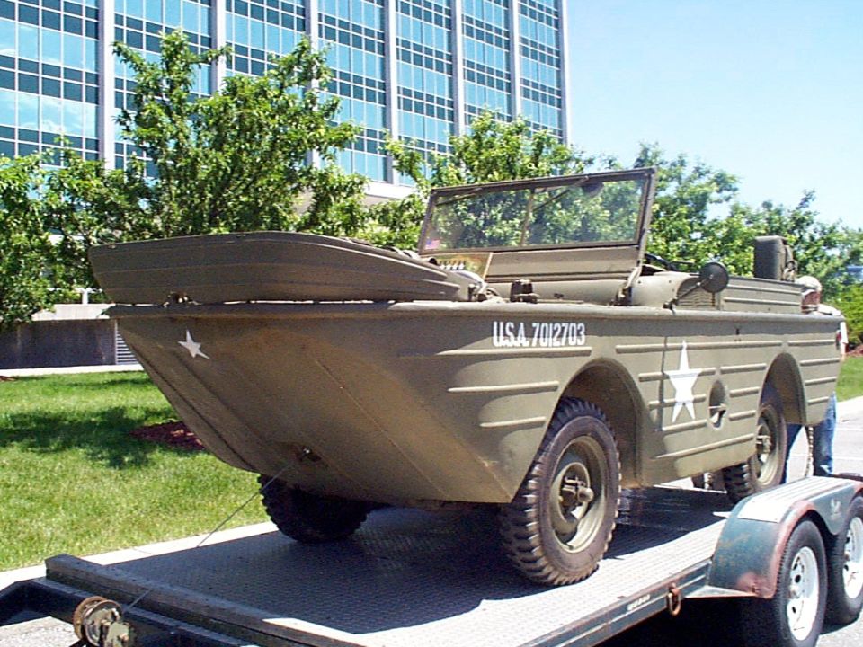 Olive drab amphibious vehicle with USA 7012703 marking on trailer