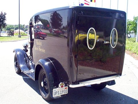 1999 Ford Taurus - This vintage United Parcel Service truck is seen from the rear, with reflections of other vehicles on its glossy black surface.