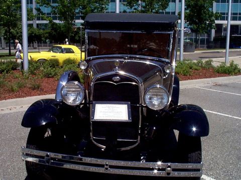 1999 Ford Taurus - A black vintage Ford is parked outside a modern building, with a yellow car visible in the background.