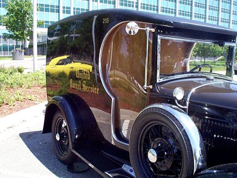 1999 Ford Taurus - Vintage United Parcel Service truck with a yellow car reflected on its glossy black side panel.