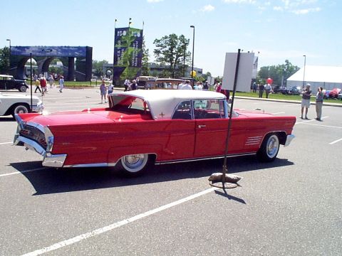 1999 Ford Taurus - A red 1958 Lincoln Continental Mark III convertible is parked at an outdoor event.