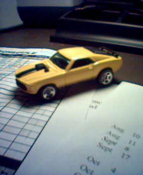 1994 Ford Bronco - A yellow toy car sits on a table with some papers.