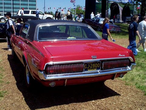 1999 Ford Taurus - A red coupe with a black roof is parked outdoors, with other vehicles and people in the background.