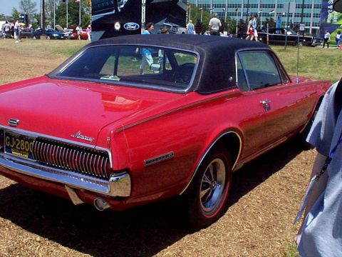 1999 Ford Taurus - A red 1969 Mercury Cougar XR7 is seen from the rear, a black vinyl top and chrome accents.