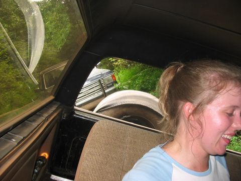 1988 Ford Bronco - View from inside a vehicle, looking out at a spare tire and the front of another vehicle.