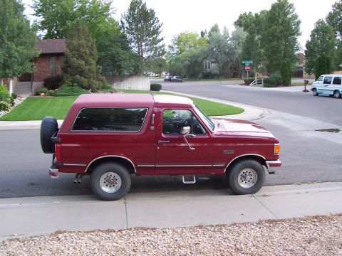 1991 Ford Bronco - A maroon Ford Bronco is parked on the side of a residential street.