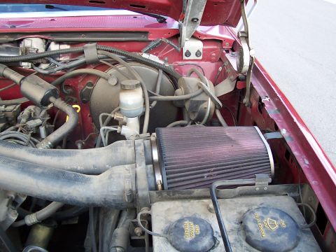 1991 Ford Bronco - The engine bay of a red 1991 Ford Bronco shows an aftermarket air filter and brake fluid reservoir.